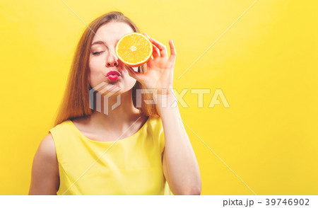 Happy young woman holding a half orange Happy young woman holding a half orange 39746902
