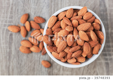 Pile of almonds nut in a while bowl against Pile of almonds nut in a while bowl against 39748393