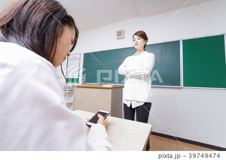 授業中にスマホを使う学生と注意する教師 39749474