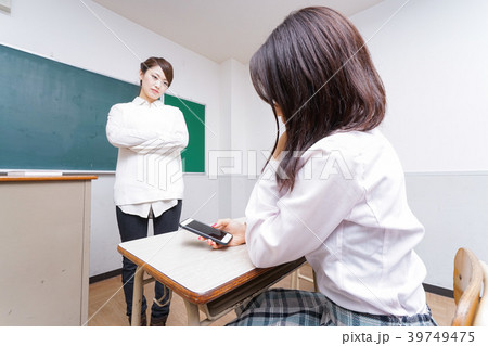 授業中にスマホを使う学生と注意する教師 39749475