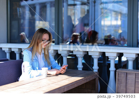 Young woman resting at street cafe with smartpnone Young woman resting at street cafe with smartpnone 39749503