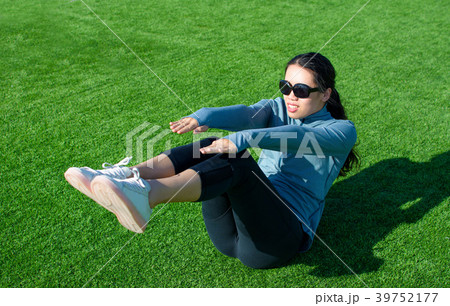 Girl doing situps on the grass, outdoor workout 39752177
