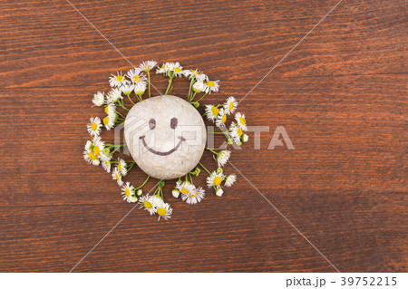 Concept, smiley stone and daisies lying on a wood 39752215