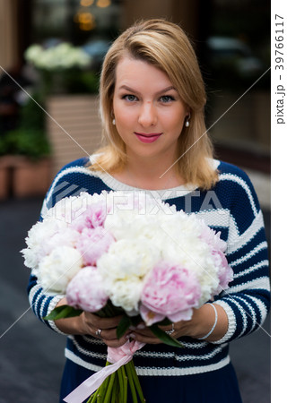 Young blonde woman in blue dress with peonies 39766117