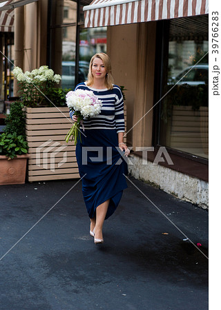 Young blonde woman in blue dress with peonies 39766283