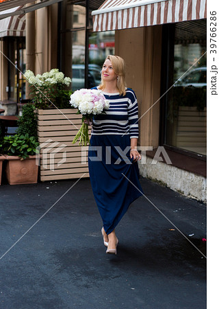Young blonde woman in blue dress with peonies 39766286