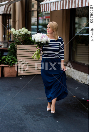 Young blonde woman in blue dress with peonies 39766287