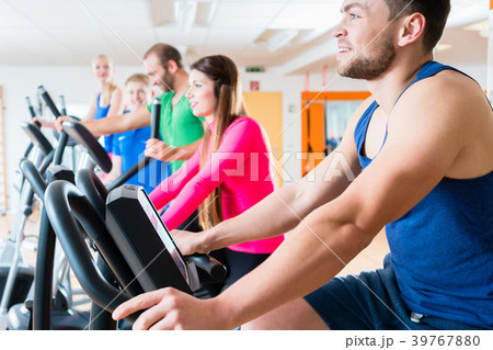 Men and women on cardio bikes in gym Men and women on cardio bikes in gym 39767880