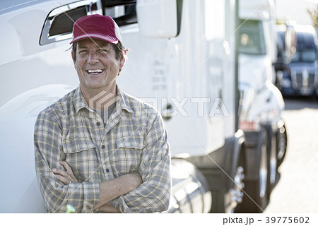 Caucasian man truck driver with his truck parked in a lot at a truck stop. Caucasian man truck driver with his truck parked in a lot at a truck stop. 39775602