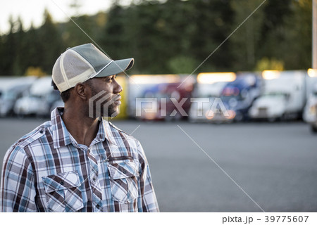 Black man truck driver near his truck parked in a parking lot at a truck stop Black man truck driver near his truck parked in a parking lot at a truck stop 39775607