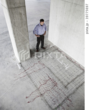 Caucasian  businessman standing in a new raw office space looking at an office layout sketched onto the floor of the space. 39775697