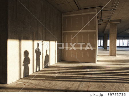 Shadows of business people cast on the sheet rock wall of a large empty raw office space. 39775736