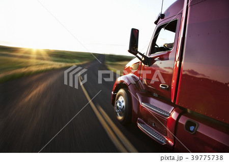 Close up side view looking forward of a  commercial truck on a highway at sunset. 39775738