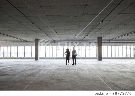 Business woman and man standing in a new empty raw office space. 39775776