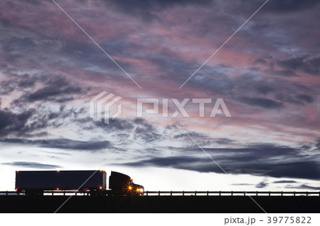 Silhouette of a  commercial truck driving on a highway at sunset. 39775822