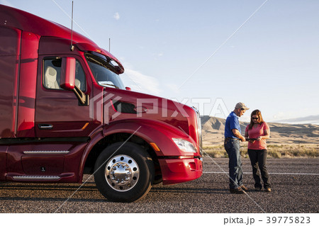 Husband and wife driving team checking their itinerary while standing in front of their  commercial truck. 39775823