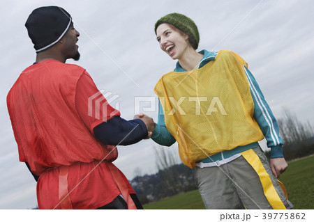 Black man and Caucasian woman team members shaking hands at a sporting event. 39775862