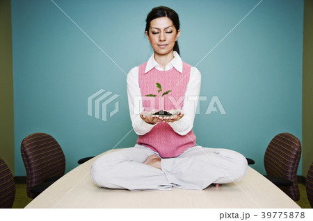 Caucasian businesswoman holding a plate with a single plant seedling. Caucasian businesswoman holding a plate with a single plant seedling. 39775878