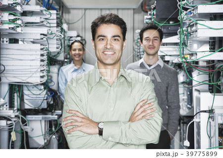Mixed race team of technicians working on computer servers in a computer server farm. Mixed race team of technicians working on computer servers in a computer server farm. 39775899