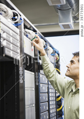 Male computer technician working on servers in a computer server farm. Male computer technician working on servers in a computer server farm. 39775901
