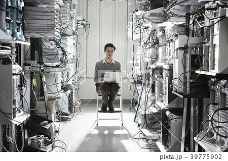 Caucasian male technician working on computer servers in a computer server farm. Caucasian male technician working on computer servers in a computer server farm. 39775902