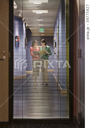 Two businesswomen walking down a hallway together. 39775927
