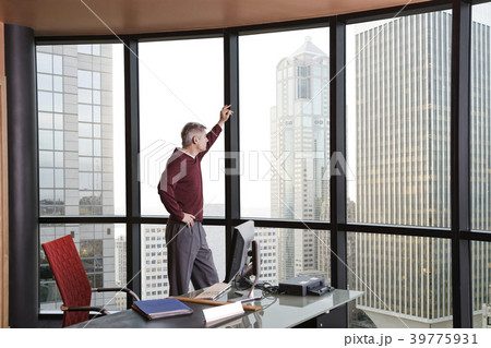 Casually dressed Caucasian businessman standing and looking at a skyline out an office window. 39775931