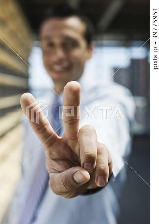 Businessman gesturing a victory sign to the camera. Businessman gesturing a victory sign to the camera. 39775951