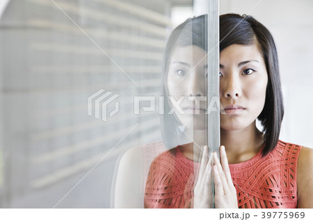 An Asian businesswoman reflected on a glass wall in an office lobby. An Asian businesswoman reflected on a glass wall in an office lobby. 39775969