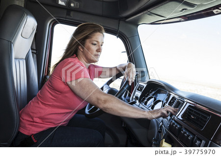 Caucasian woman driver parked and using the GPS mapping device in the cab of a  commercial truck. 39775970