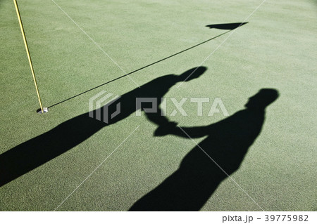 Shadow of golfers and the flag on a green of a golf course. 39775982