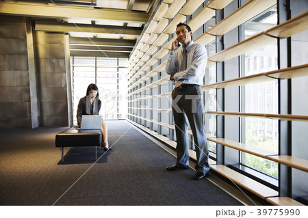 Businesswoman and businessman working in a lobby of a large office building. Businesswoman and businessman working in a lobby of a large office building. 39775990