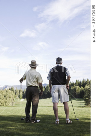 Viewed from behind, a pair of senior golfers check out a fairway on the golf course. Viewed from behind, a pair of senior golfers check out a fairway on the golf course. 39775999