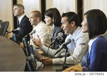 A political meeting with a mixed race group of people at microphones. A political meeting with a mixed race group of people at microphones. 39776002