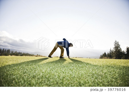 An Asian senior man teeing up a golf ball and ready to swing. 39776016