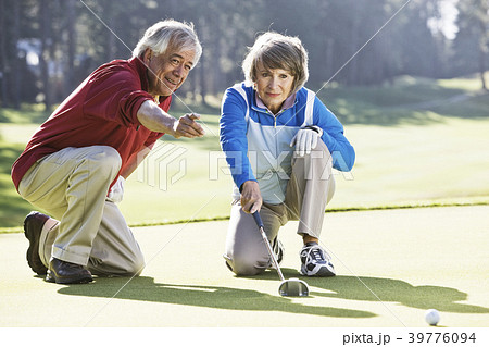 Senior couple discussing the direction of the putt on the green of a golf course. 39776094