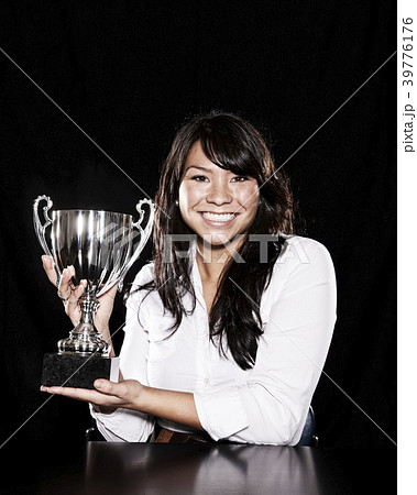 Studio portraits of an Asian woman holding a trophy. 39776176