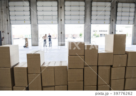 Team of workers check out inventory in front of loading dock doors in a new warehouse. Team of workers check out inventory in front of loading dock doors in a new warehouse. 39776262