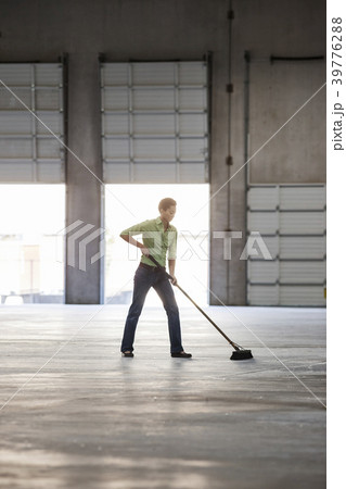 Black woman sweeping up in an empty warehouse space. Black woman sweeping up in an empty warehouse space. 39776288