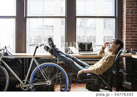 Hispanic man at his office workstation with a bicycle. 39776305