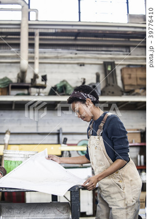 Black woman factory worker going over project plans in a sheet metal factory. 39776410
