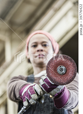 Black woman factory worker using a metal grinding tool in a sheet metal factory. 39776422