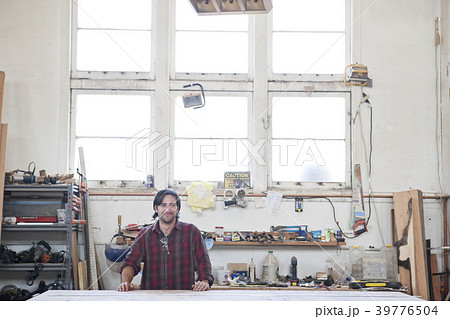 View of a Caucasian man factory worker wearing safety glasses in a woodworking factory. 39776504