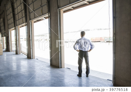 Caucasian man in shirt and tie standing in loading dock door of new empty warehouse anticipating the arrival of the first truck load new business. 39776518