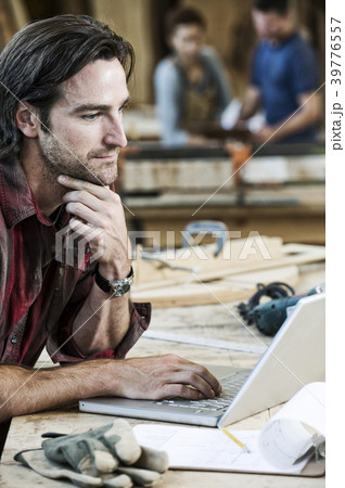Caucasian man factory worker working on a lap top computer at a work station in a woodworking factory. 39776557