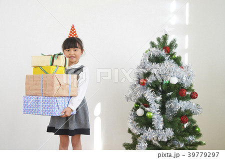 クリスマス ツリーとプレゼントを持つ女の子の写真素材
