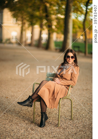A beautiful girl in a brown coat sits in the 39783407