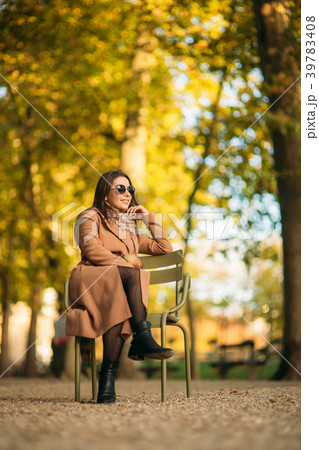 A beautiful girl in a brown coat sits in the 39783408