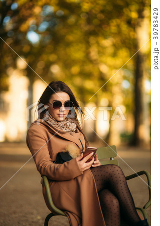 A young girl in a brown coat sits in the middle of 39783429