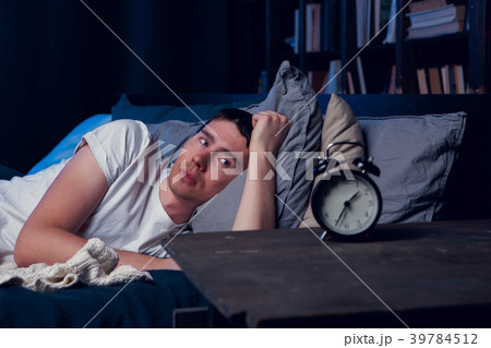Picture of brunet with insomnia in bed with alarm 39784512